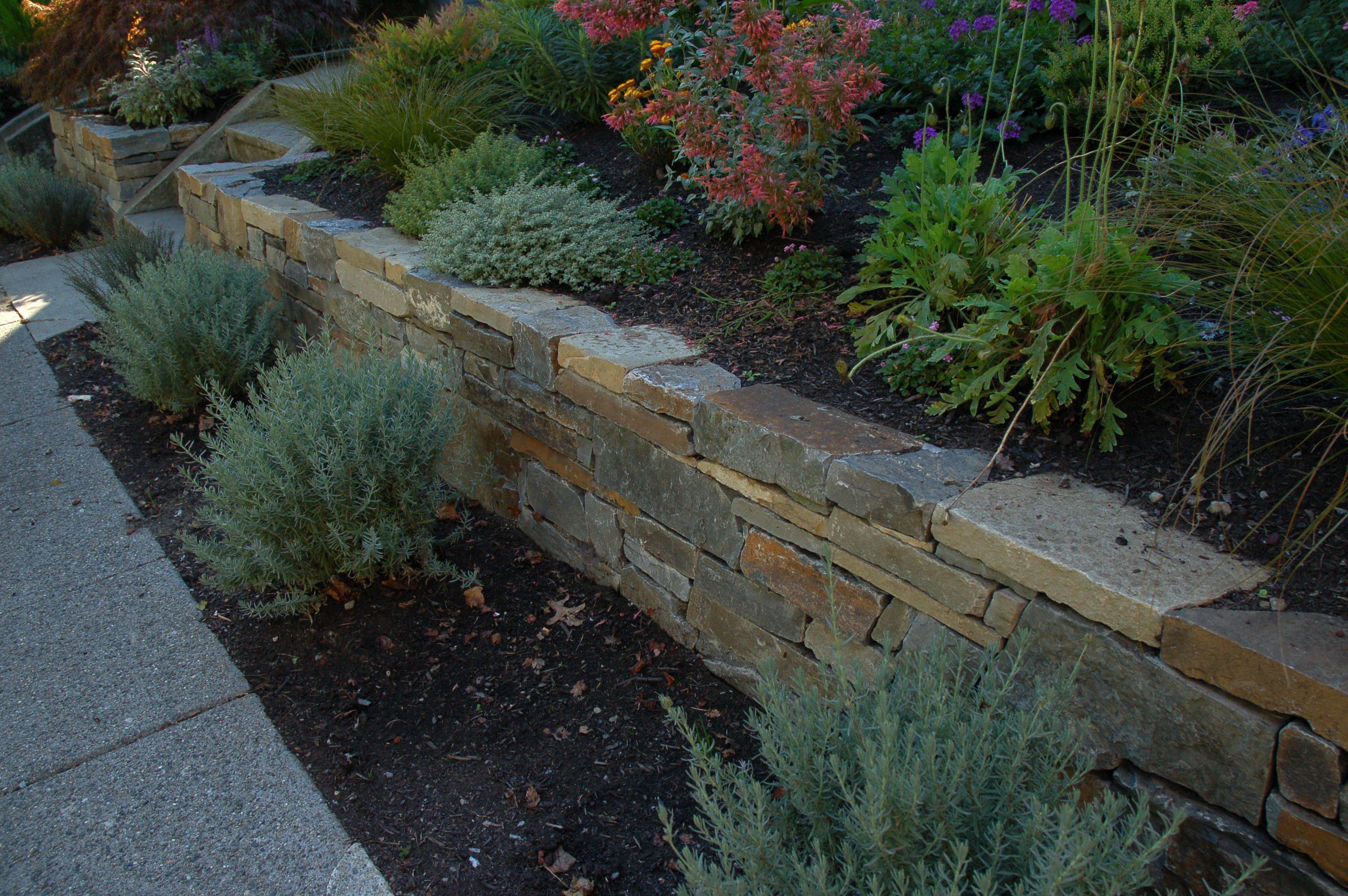 A Drystacked Stone Wall And Brick Pathway